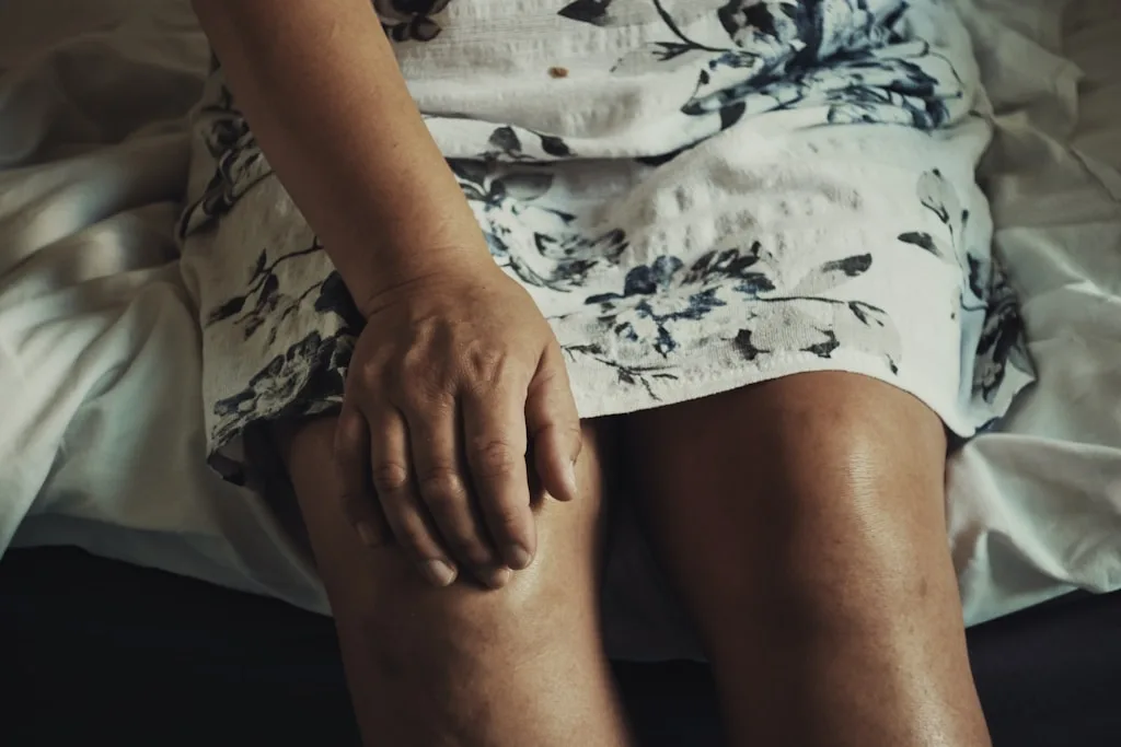 Senior trzymający się za bolące kolano podczas wstawania z krzesła
